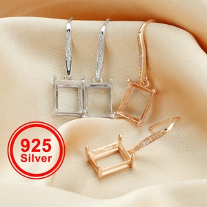 May include: Three silver and gold earring blanks with a rectangular bezel setting and a dangle design. The earrings are on a light brown fabric background. The text "925 Silver" is in a red circle.