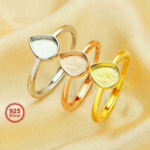 Peut inclure: Trois bagues en argent avec des montures en forme de larme. Les bagues sont empilées les unes sur les autres. Les montures sont vides et prêtes à être remplies de résine ou d'autres matériaux. Les bagues sont en argent 925.