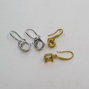 May include: Two pairs of earring settings, one pair is silver and the other is gold. Each setting is oval shaped and has a hook.