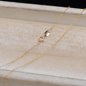 May include: A gold chain necklace with a lobster clasp closure. The chain is delicate and has a fine, linked design.