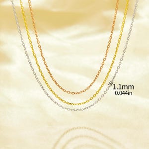 May include: Three gold chains of different colors, silver, gold, and rose gold, on a white background. The chains are all the same style, with small, round links. The chains are layered on top of each other, with the silver chain on the bottom, the gold chain in the middle, and the rose gold chain on top. The chains are 1.1 mm thick, or 0.044 inches.