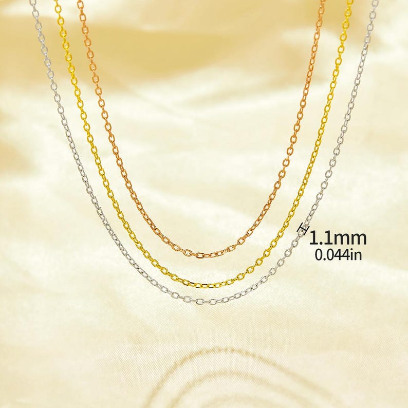 May include: Three gold chains of different colors, silver, gold, and rose gold, on a white background. The chains are all the same style, with small, round links. The chains are layered on top of each other, with the silver chain on the bottom, the gold chain in the middle, and the rose gold chain on top. The chains are 1.1 mm thick, or 0.044 inches.