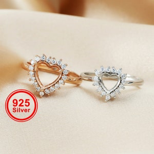 Può includere: Due anelli d'argento con un design a forma di cuore. Gli anelli sono adornati con piccole pietre trasparenti. L'anello a sinistra è di colore oro rosa. L'anello a destra è di colore argento. 925 Argento.