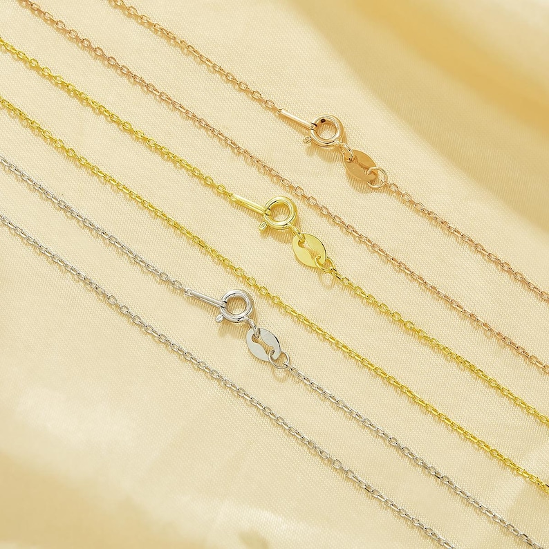 May include: Five different gold chains of varying lengths and thicknesses. The chains are arranged in a fan shape and are all connected to a clasp.