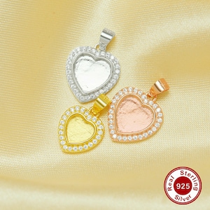 Puede incluir: Tres colgantes de plata en forma de corazón con un centro transparente, dorado y oro rosa. Cada colgante está rodeado por una fila de piedras de circonita cúbica transparentes. Los colgantes están sobre un fondo dorado claro.