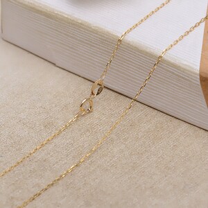 May include: A gold chain necklace with a lobster clasp closure. The chain is delicate and has a fine, polished finish.