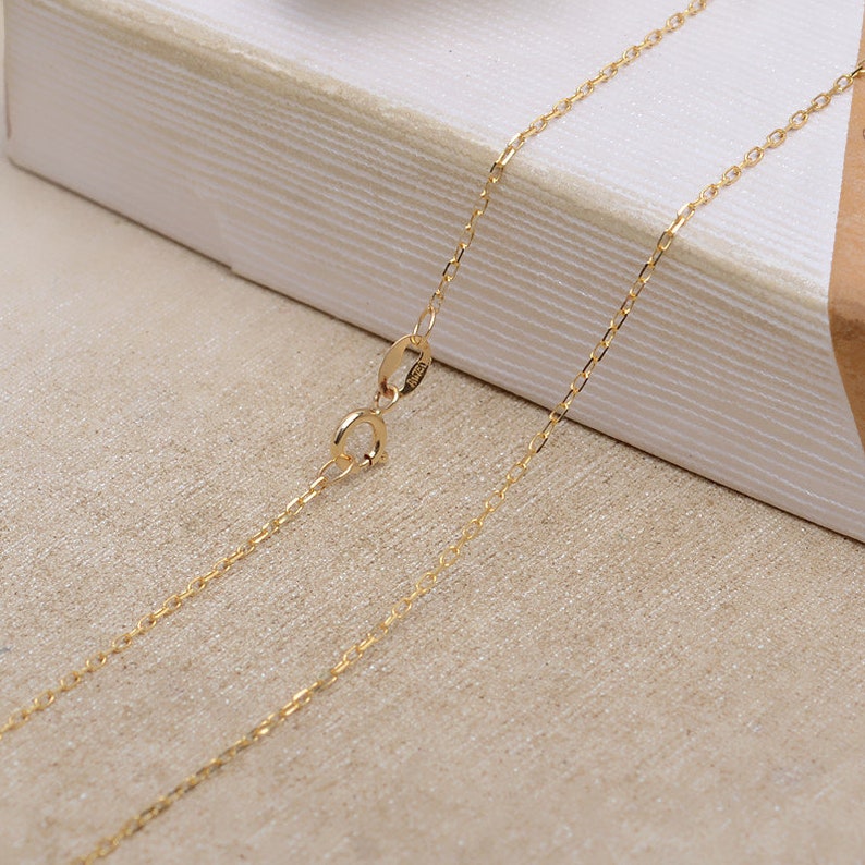 May include: A gold chain necklace with a lobster clasp closure. The chain is delicate and has a fine, polished finish.