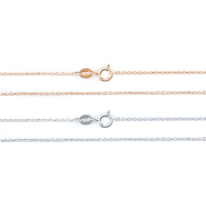 May include: Two delicate chain necklaces, one in rose gold and one in silver, with lobster claw clasps. The chains are both thin and have a delicate, feminine look.
