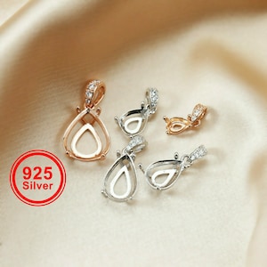 May include: Five silver and rose gold pendant settings with clear cubic zirconia stones. The settings are in the shape of a teardrop and are designed to hold a gemstone.