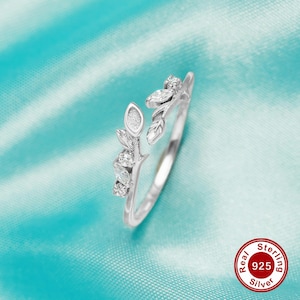May include: A silver ring with a delicate leaf design and small clear stones. The ring is open and adjustable. Real Sterling 925 Silver.