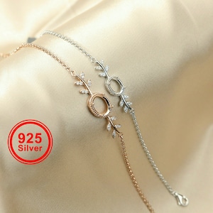 May include: Two silver bracelets with delicate leaf designs and a circle charm. The bracelets are on a light brown fabric background. The text "925 Silver" is visible in the lower left corner of the image.