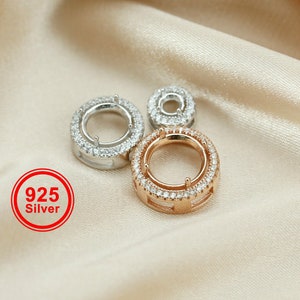 Peut inclure: Trois anneaux en argent et or avec des pierres en zircone cubique transparentes. Les anneaux sont sur un fond de tissu brun clair. Les anneaux sont de tailles différentes. Le plus grand anneau est de couleur or et porte un poinçon en argent 925.