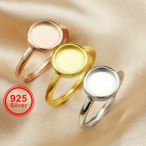 Peut inclure: Trois bagues en argent avec des montures rondes en or rose, or et argent. Les bagues sont présentées sur une surface satinée. Le texte "925 Silver" est dans un cercle rouge.