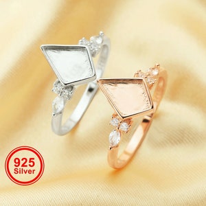 May include: Two silver and rose gold rings with a diamond-shaped setting. The rings are adorned with small clear stones. The silver ring has the number 925 and the word "Silver" printed on it.