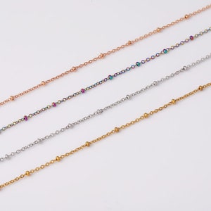 May include: Four different chain necklaces with small beads. The chains are gold, silver, rose gold, and rainbow.
