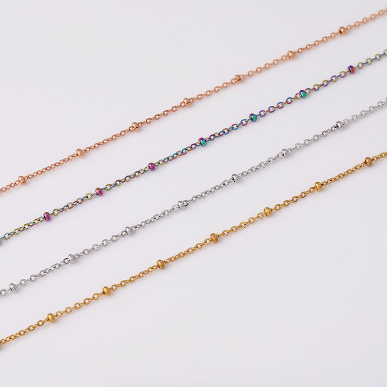 May include: Four different chain necklaces with small beads. The chains are gold, silver, rose gold, and rainbow.