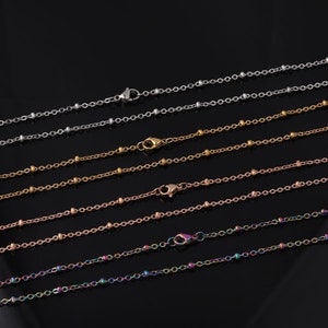 May include: A set of six delicate beaded chains in various colors, including silver, gold, rose gold, and rainbow. The chains are all the same length and have a lobster clasp closure.