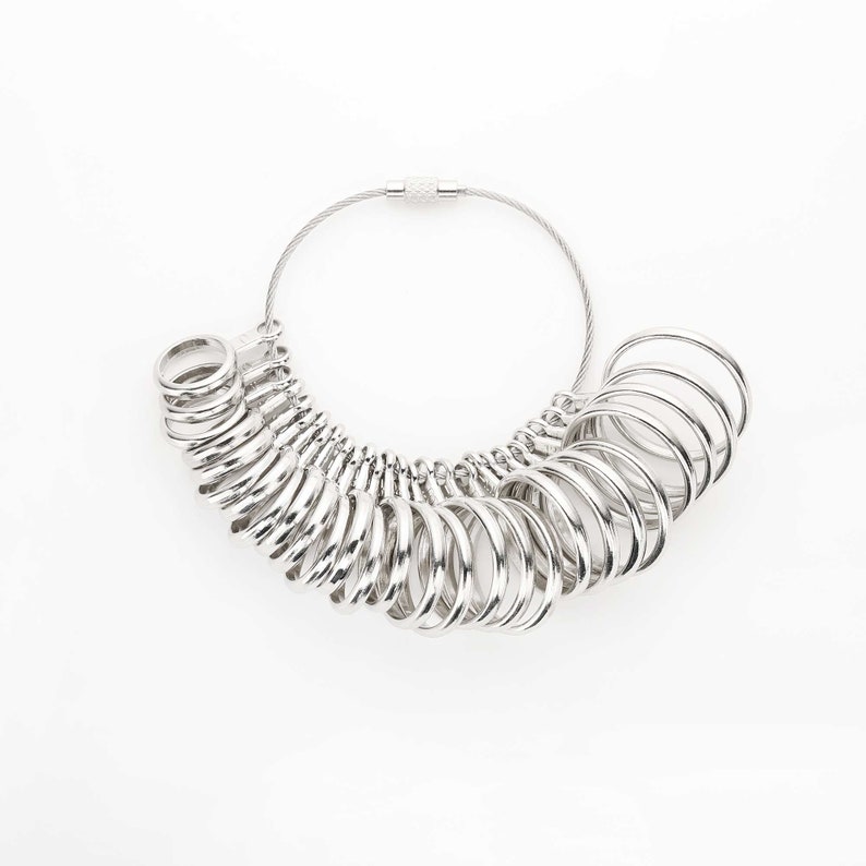 May include: A silver ring sizer with a chain and clasp. The sizer has a series of rings of different sizes.