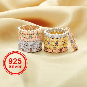 May include: Stackable sterling silver rings with a honeycomb design. Each ring features a different color gemstone. The rings are in shades of silver, rose gold, and gold. The image includes a red circle with the text "925 Silver".