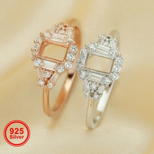 May include: Two silver rings with a square setting, one ring is rose gold and the other is silver. Both rings are adorned with small clear cubic zirconia stones.