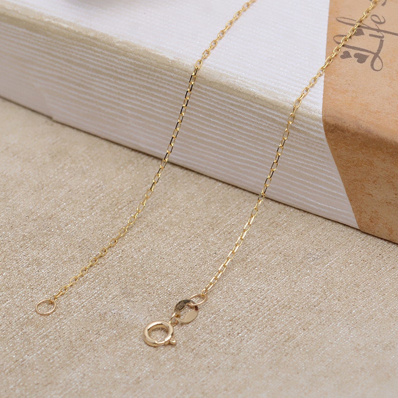 May include: A gold chain necklace with a lobster clasp closure. The chain is delicate and has a simple design.
