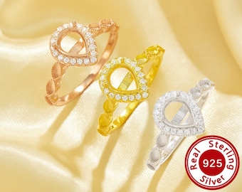 May include: Three silver rings with teardrop-shaped settings encrusted with clear cubic zirconia stones. The rings are displayed on a cream-coloured fabric background. The text "Real 925 Sterling Silver" is visible in the lower right corner of the image.