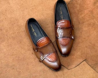 May include: A pair of brown leather double monk strap shoes featuring a textured crocodile-embossed pattern on the vamp and strap. The interior footbed is black and displays the text FUTURE FEET in gold lettering on the heel area.