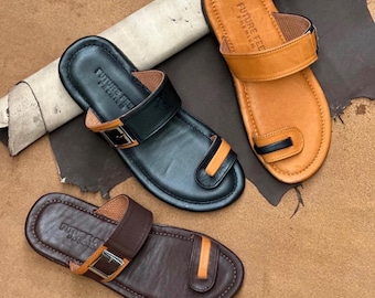 May include: Three leather sandals in black, tan, and dark brown, each featuring a toe loop, a side buckle strap, and the text "FUTURE FEE PREMIUM" on the footbed. The text "SHEEP LEATHER MASTERPIECE" is visible at the top of the image.