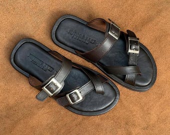 May include: A pair of dark brown leather sandals featuring two adjustable straps with silver-toned metal buckles and a toe loop design. The footbed is dark brown with the text Future Feet Premium embossed on the heel area of each sandal.