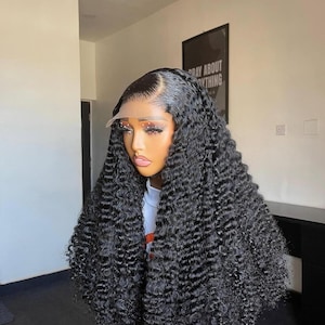 May include: A black curly wig with a lace front. The wig features a natural-looking hairline and voluminous, tightly curled strands. The hair is styled with a side part and falls in loose waves.