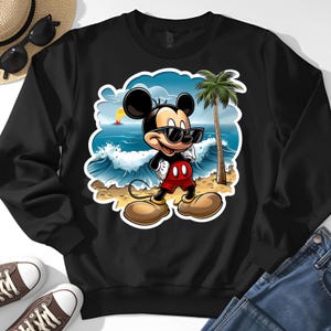 May include: Black sweatshirt featuring a cartoon Mickey Mouse wearing sunglasses, red shorts, and large shoes, standing on a beach with a palm tree and ocean waves. Sunglasses and a straw hat are visible.