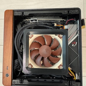 Peut inclure: Un bo&icirc;tier d'ordinateur compact avec un panneau avant en bois. &Agrave; l'int&eacute;rieur, on aper&ccedil;oit un refroidisseur de processeur avec un grand ventilateur marron, une carte graphique et des c&acirc;bles. Le bo&icirc;tier est ouvert, r&eacute;v&eacute;lant les composants internes.