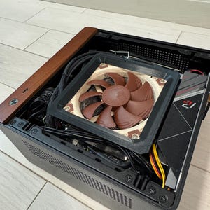 May include: A black computer case with a brown wooden top and a brown fan. The fan has brown blades and is mounted inside the case. Cables and other components are visible inside the case.