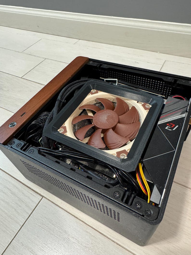 Peut inclure: Un bo&icirc;tier d'ordinateur noir avec un dessus en bois marron et un ventilateur marron. Le ventilateur a des pales marron et est mont&eacute; &agrave; l'int&eacute;rieur du bo&icirc;tier. Des c&acirc;bles et d'autres composants sont visibles &agrave; l'int&eacute;rieur.