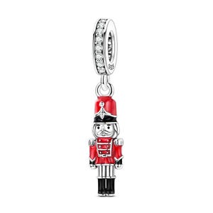 May include: A silver charm bead featuring a nutcracker figure with red, black, and white enamel details. The cylindrical top section is encrusted with small clear stones and is stamped with the text S925, indicating sterling silver composition.