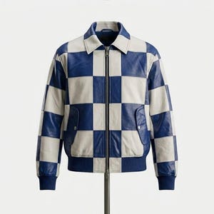 Peut inclure: Une veste en cuir arborant un motif à carreaux bleu et blanc sur l'ensemble. La veste comprend un col classique, une fermeture éclair métallique sur toute la longueur, deux poches latérales à bouton-pression, ainsi que des poignets et un ourlet côtelés bleu uni.