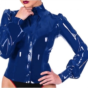 Pode incluir: Uma camisa de manga comprida com botões feita de material de látex azul profundo e brilhante. A camisa apresenta um colarinho estruturado, um corpete ajustado e mangas compridas com punhos abotoados. A superfície tem um acabamento reflexivo.