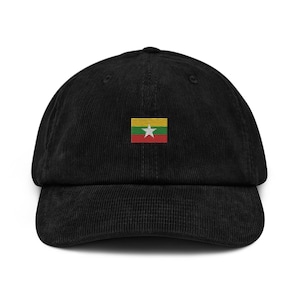 Op de afbeelding: Zwarte corduroy baseballpet met de vlag van Myanmar geborduurd op de voorkant. Het vlagontwerp heeft horizontale strepen in geel, groen en rood, met een witte ster in het midden. De pet heeft een gebogen klep en een verstelbare band.