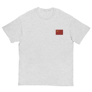 Op de afbeelding: Een lichtgrijs t-shirt met de vlag van China op de linkerborst. De vlag is rood met vijf gele sterren. Het t-shirt heeft korte mouwen en een ronde hals.