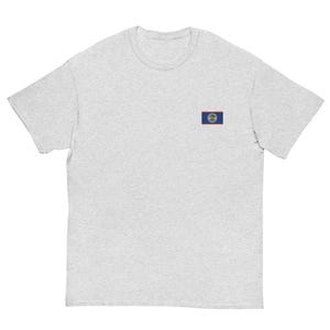 May include: A light heather gray short-sleeve t-shirt featuring a small, rectangular embroidered patch on the left chest. The patch displays the flag of Belize, which consists of horizontal blue and red stripes with a central white circular emblem.