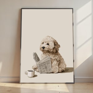 Könnte beinhalten: Ein gerahmter Kunstdruck, der einen hellbraunen, lockigen Hund zeigt, der aufrecht sitzt und eine aufgeschlagene Zeitung mit seinen Vorderpfoten hält. Eine kleine weiße Kaffeetasse steht neben dem Hund auf einem einfarbigen, hellbeigen Hintergrund.