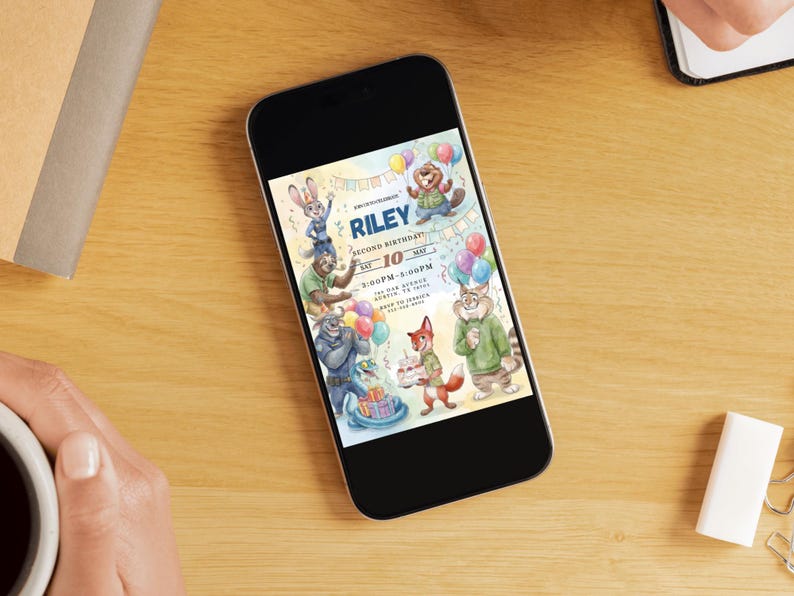 Pu&ograve; includere: Uno smartphone mostra un invito di compleanno colorato con personaggi di animali dei cartoni animati. L'invito include il nome "Riley", la data "10 maggio" e i dettagli dell'evento. Il telefono &egrave; appoggiato su una superficie di legno.
