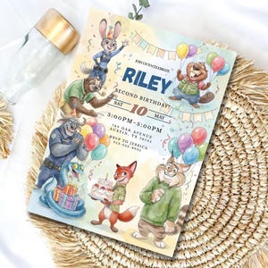 Pu&ograve; includere: Un colorato invito di compleanno con personaggi dei cartoni animati. L'invito recita "RILEY SECOND BIRTHDAY! SAT 10 MAY 3:00PM-5:00PM". Il design include palloncini e vari personaggi animali.
