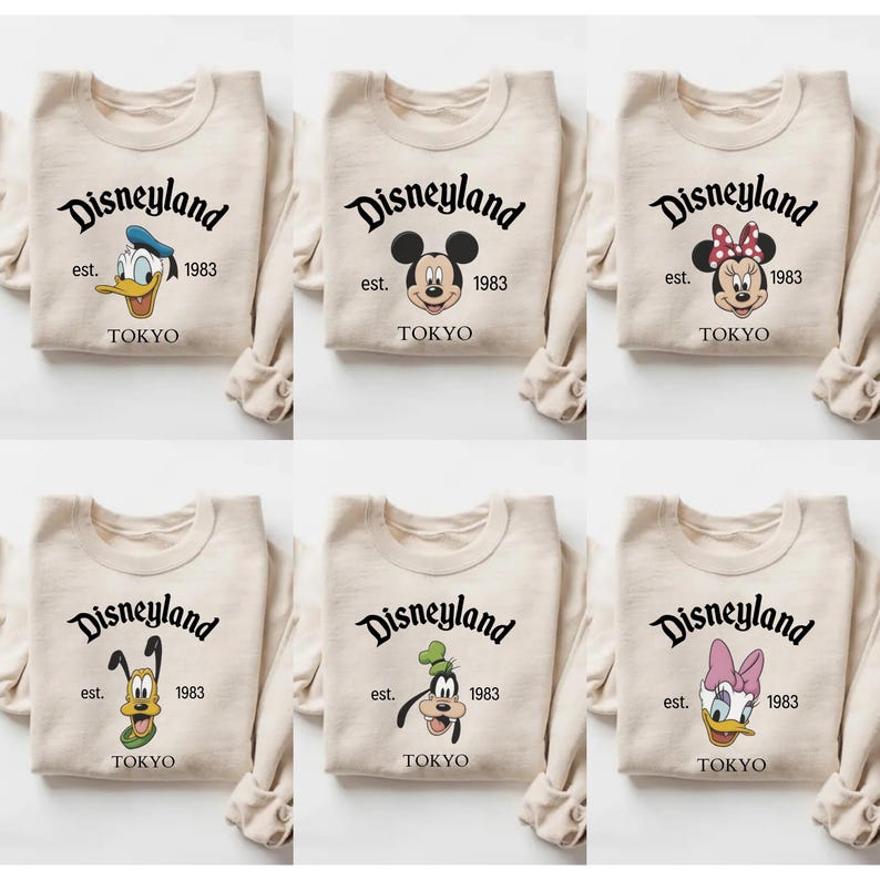Pu&ograve; includere: Sei felpe beige con il logo Disneyland e vari personaggi Disney. Ogni felpa ha il testo "Disneyland est. 1983 TOKYO". I personaggi includono Paperino, Topolino, Minnie, Pluto, Pippo e Paperina.