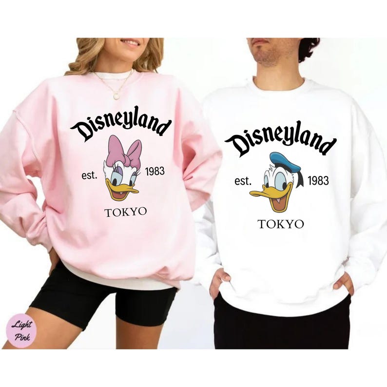 Pu&ograve; includere: Felpe Disneyland rosa e bianche. La felpa rosa presenta Paperina, e la felpa bianca presenta Paperino. Entrambe le felpe hanno il logo Disneyland, l'anno 1983 e la citt&agrave; di Tokyo.