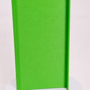 May include: A bright lime green, rectangular, upright object with a smooth, flat front surface and a vertical, protruding edge along the right side. The object features a consistent, solid color finish and a clean, structured, geometric design.