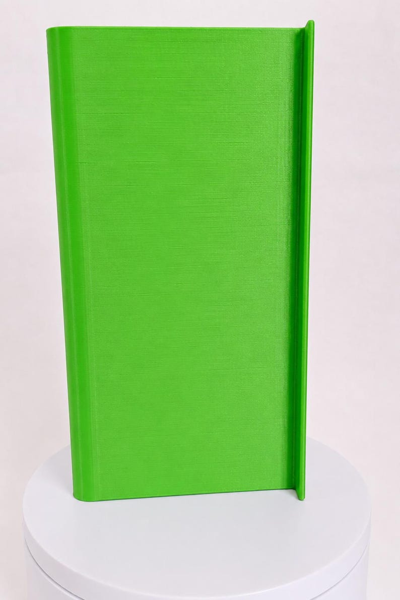 May include: A bright lime green, rectangular, upright object with a smooth, flat front surface and a vertical, protruding edge along the right side. The object features a consistent, solid color finish and a clean, structured, geometric design.