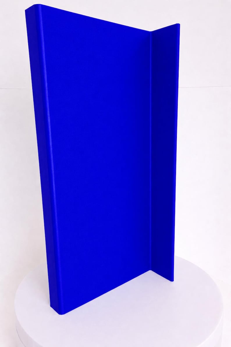 May include: A tall, vibrant blue vertical panel with a smooth, matte finish. The object features a distinct L-shaped profile, consisting of one wide front-facing section and a narrower side section, creating a sharp, clean right-angle corner.