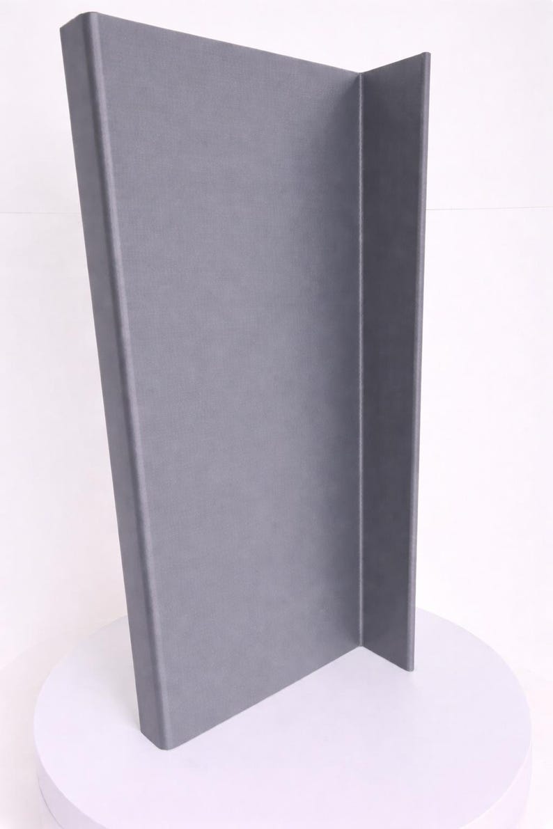 May include: A tall, L-shaped display board with a smooth, matte gray finish. The structure consists of two rectangular panels joined at a right angle, creating a vertical corner profile that stands upright on a circular white base.