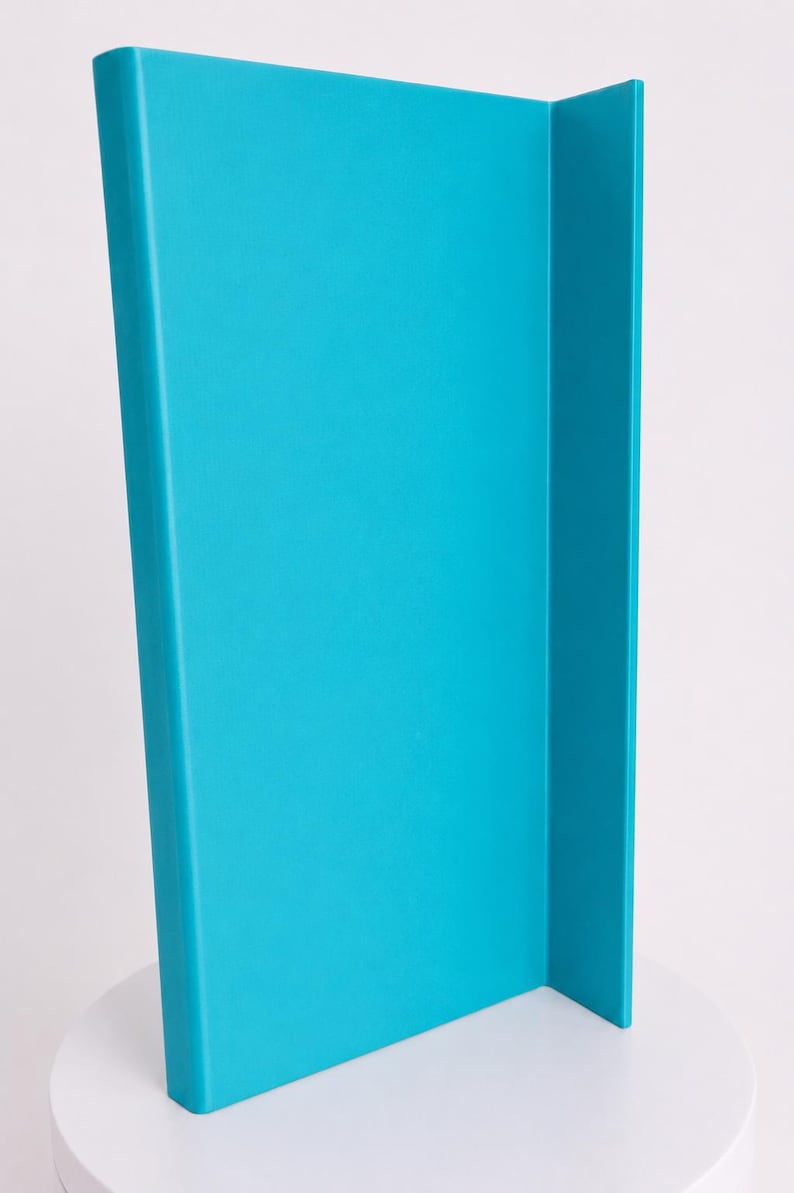 May include: A bright turquoise L-shaped panel with a smooth, matte finish. The object features a tall, vertical rectangular section connected to a shorter, perpendicular side panel, creating a clean, angular structure with rounded edges.